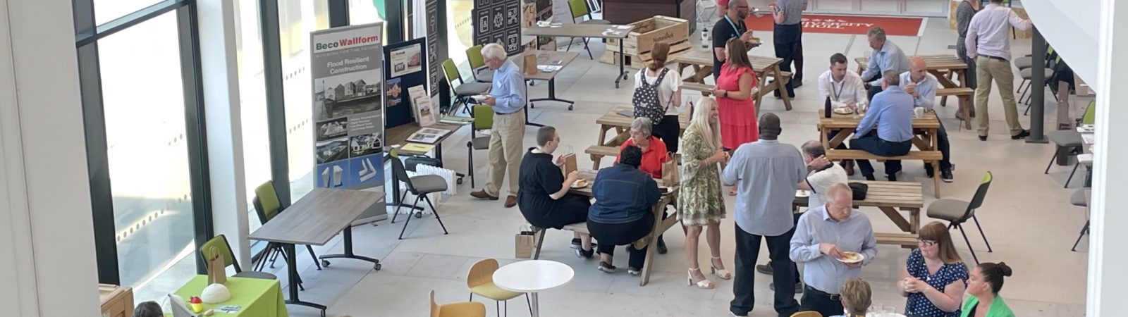 A view pf the Flood Innovation Showcase, taken from the 1st floor, showing guests and exhibitors networking over coffee